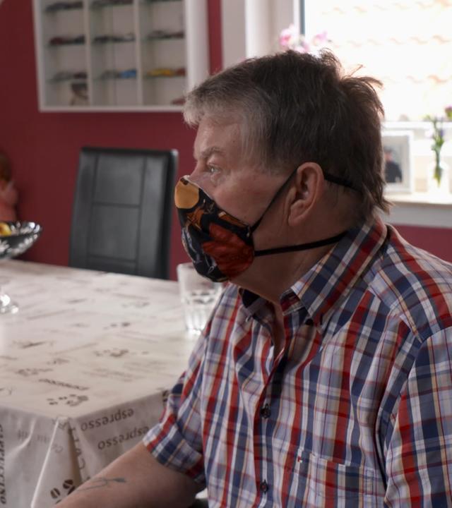 Mann mit Maske im Rollstuhl
