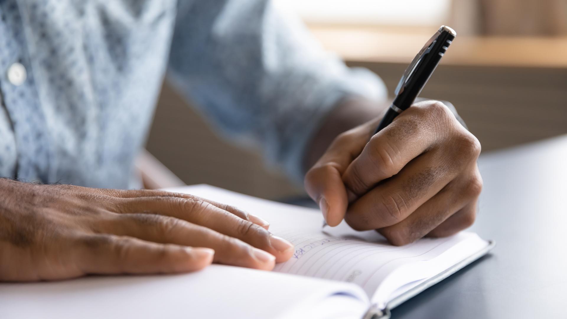 Ein Mann schreibt in ein Notizbuch