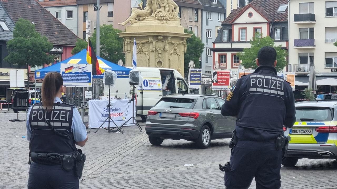 Zwei Polizisten stehen vor dem Mannheimer Markplatz nach einem Messerangriff