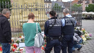 Baden-Württemberg, Mannheim: Zahlreiche Personen, darunter Polizisten, stehen in unmittelbarer Nähe des Tatorts vor niedergelegten Kerzen und Blumen.