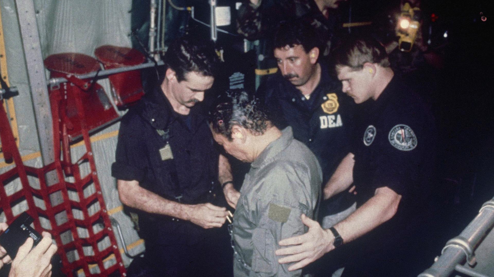 Archivfoto vom 4. Januar 1990: Manuel Noriega wird an Bord eines C-130-Transportflugzeugs beobachtet, während Beamte der US-Drogenbekämpfungsbehörde ihm Ketten um die Taille legen.