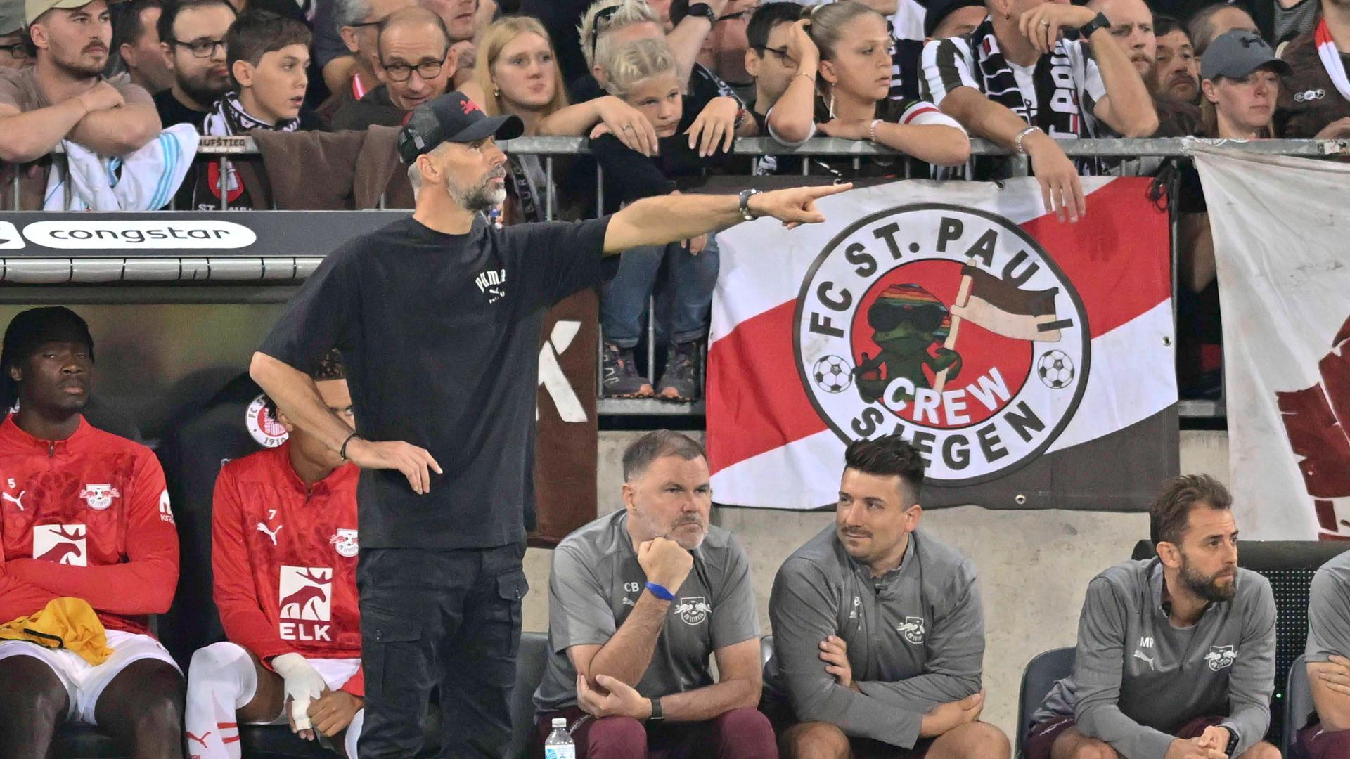 FC St. Pauli - RB Leipzig am 22.09.2024: RB-Trainer Marco Rose deutet Richtung Spielfeld. Im Hintergrund St.-Pauli-Fans auf der Tribüne.