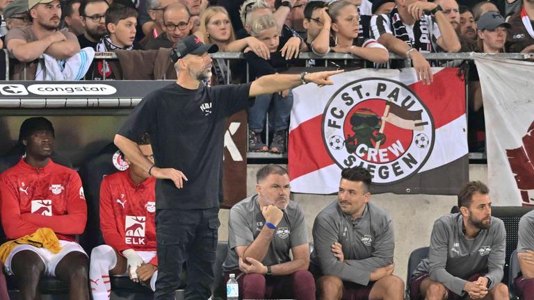 FC St. Pauli - RB Leipzig am 22.09.2024: RB-Trainer Marco Rose deutet Richtung Spielfeld. Im Hintergrund St.-Pauli-Fans auf der Tribüne.