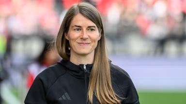 Die Fußballerin und Trainerin Marie-Louise Eta blickt lächelnd nach rechts.