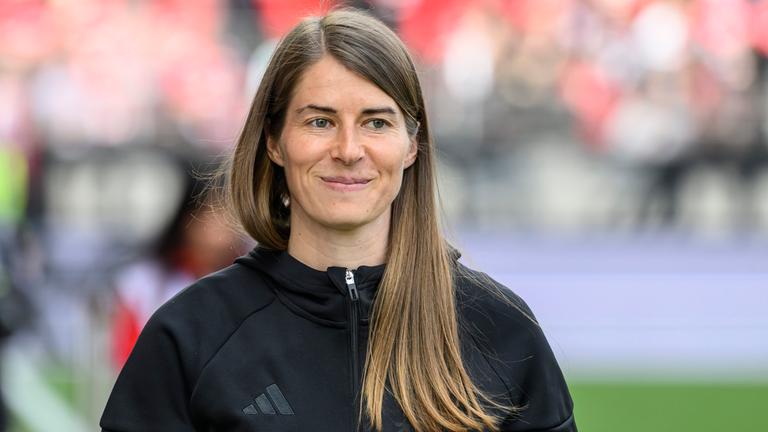 Die Fußballerin und Trainerin Marie-Louise Eta blickt lächelnd nach rechts.