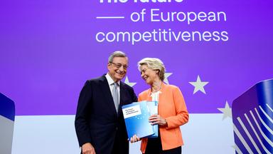 Früherer EZB-Chef Mario Draghi überreicht Ursula von der Leyen auf der Bühne den Bericht zur EU-Wirtschaft.
