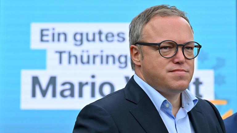 Mario Voigt, Landesvorsitzender der CDU in Thüringen, steht vor einem großen Banner der CDU und schaut in die Ferne.