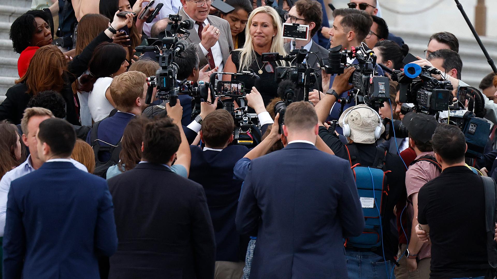 Die republikanische Abgeordnete Majorie Taylor Greene steht von Reportern umzingelt auf den Stufen des US-Kapitols. 