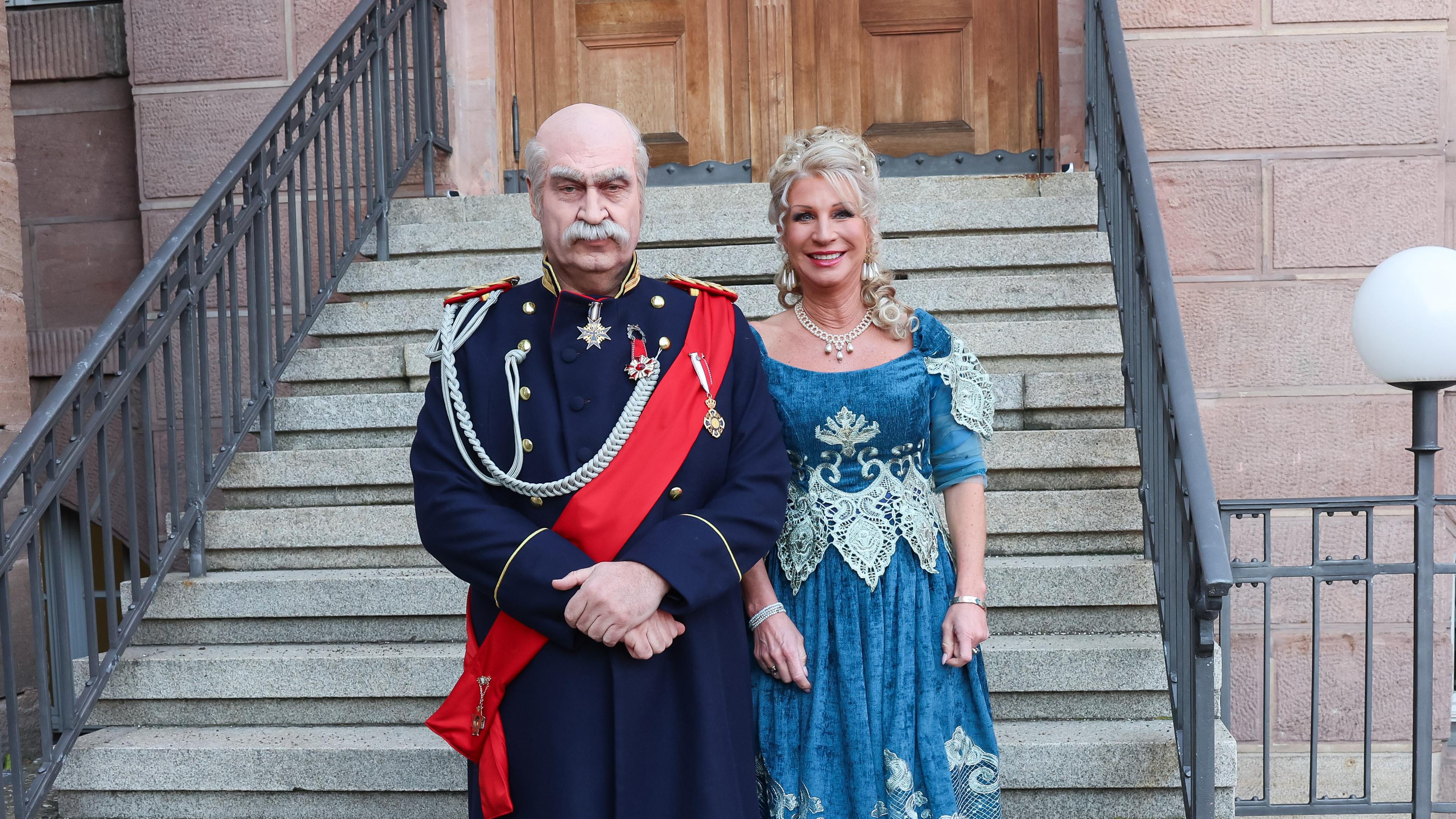 Bayern, Nürnberg: Bayerns Ministerpräsident Markus Söder (CSU, l) und Karin Baumüller-Söder gehen als Reichskanzler Otto von Bismarck und eine Dame aus der Zeit Bismarcks zum Franken-Fasching und stehen für ein Foto auf einer Treppe am Staatstheater Nürnberg.