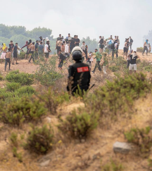 Marokko, Fnideq: Ein Angehöriger der marokkanischen Sicherheitskräfte steht Wache, während Menschen  versuchen, von der nordmarokkanischen Stadt Fnideq in die spanische Exklave Ceuta zu gelangen.