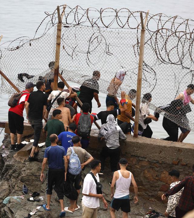 Menschen versammeln sich entlang des Zauns nahe dem Ort von Zusammenstößen bei Fnideq an der Grenze zwischen Marokko und Spanien.