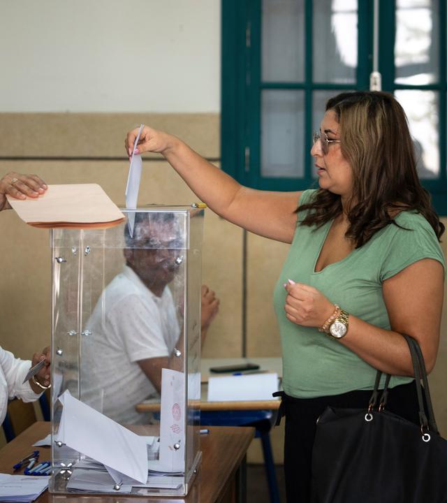 Eine Frau gibt ihren Wahlschein ab.