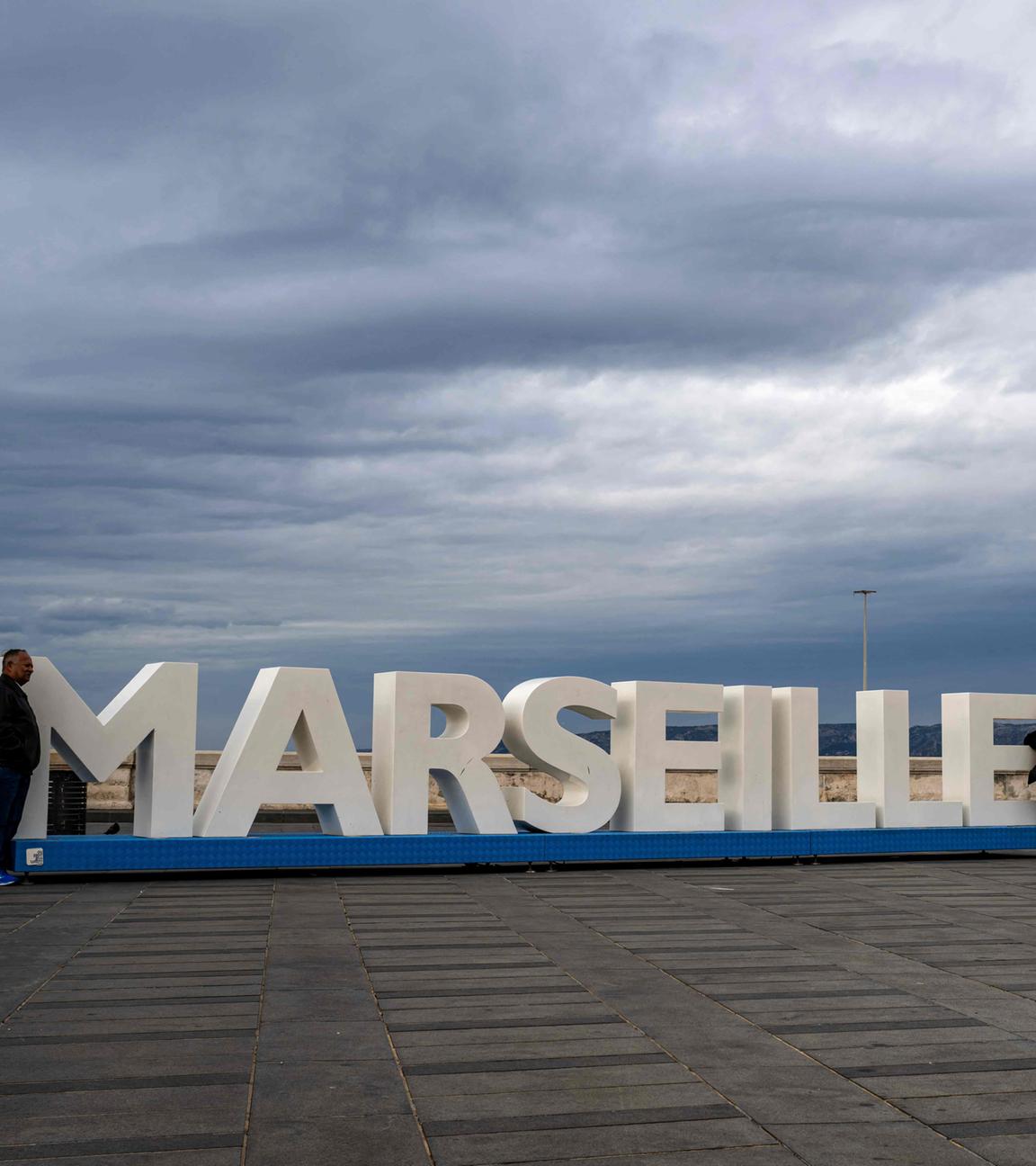 Menschen posieren neben einem großen Aufsteller mit dem Wort Marseille.