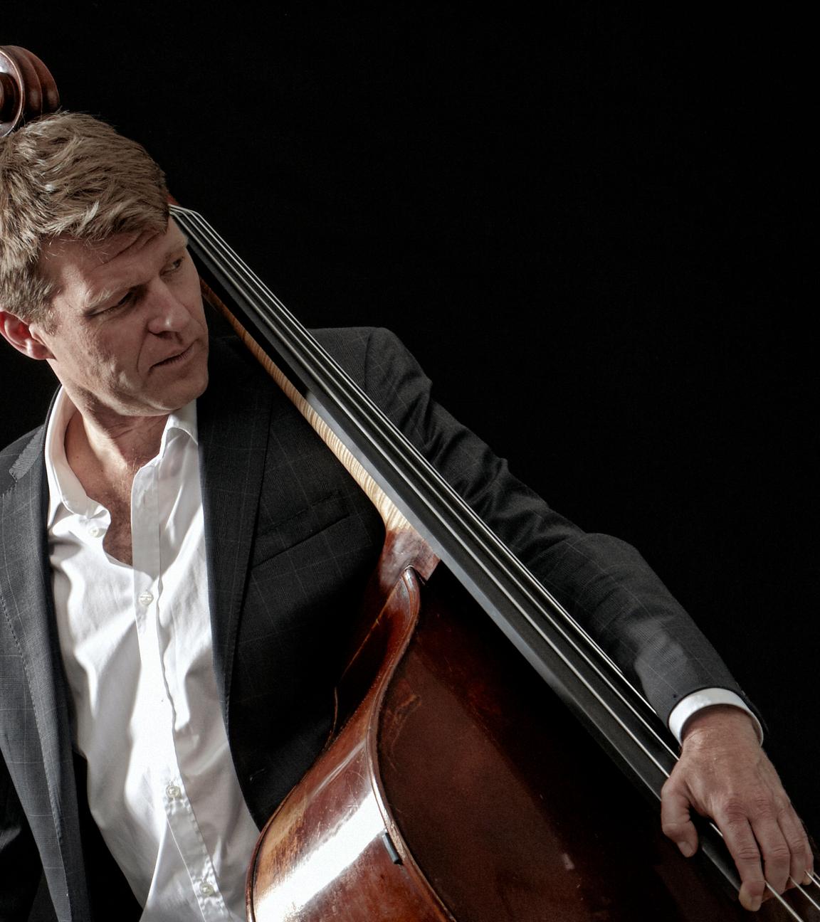 Der Bassist Martin Wind mit Kontrabass, seitlich den Kontrabass auf der Hüfte tragend.
