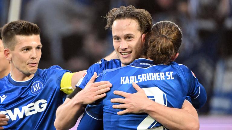 Die Karlsruher Fußballer Marvin Wanitzek (l-r), Christoph Kobald und Sebastian Jung, bejubeln den Treffer zum 2:1 durch Christoph Kobald am 10.04.2026.