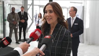 Auf dem Bild zu sehen: Königin Mary die bei einer Konferenz in Mikrofone spricht.