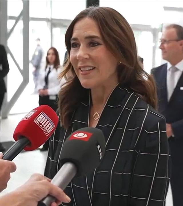 Auf dem Bild zu sehen: Königin Mary die bei einer Konferenz in Mikrofone spricht.