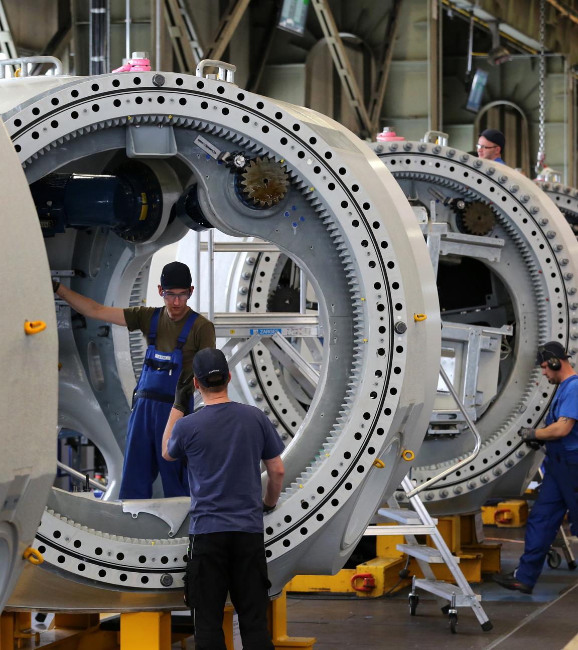 Es sind drei Männer zu sehen, die gerade große Maschinen anfertigen.