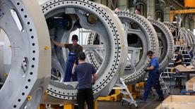 Three people are seen building a large machine.
