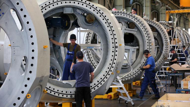 Es sind drei Männer zu sehen, die gerade große Maschinen anfertigen.