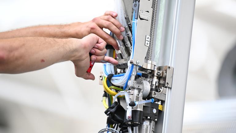 Baden-Württemberg, Bietigheim-Bissingen: Ein Arbeiter des Maschinenbauers Dürr montiert am Stammsitz einen Roboterarm für eine Lackieranlage für Fahrzeuge.