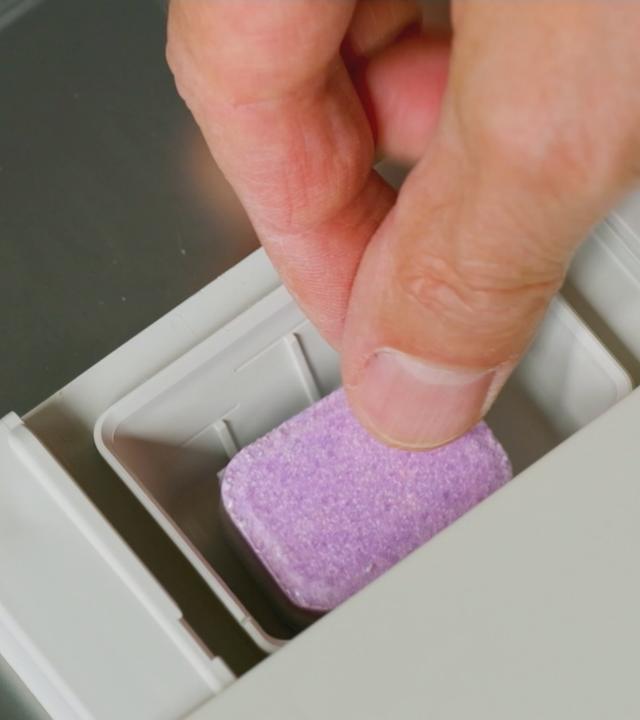 Person legt Tab in Spülmaschine
