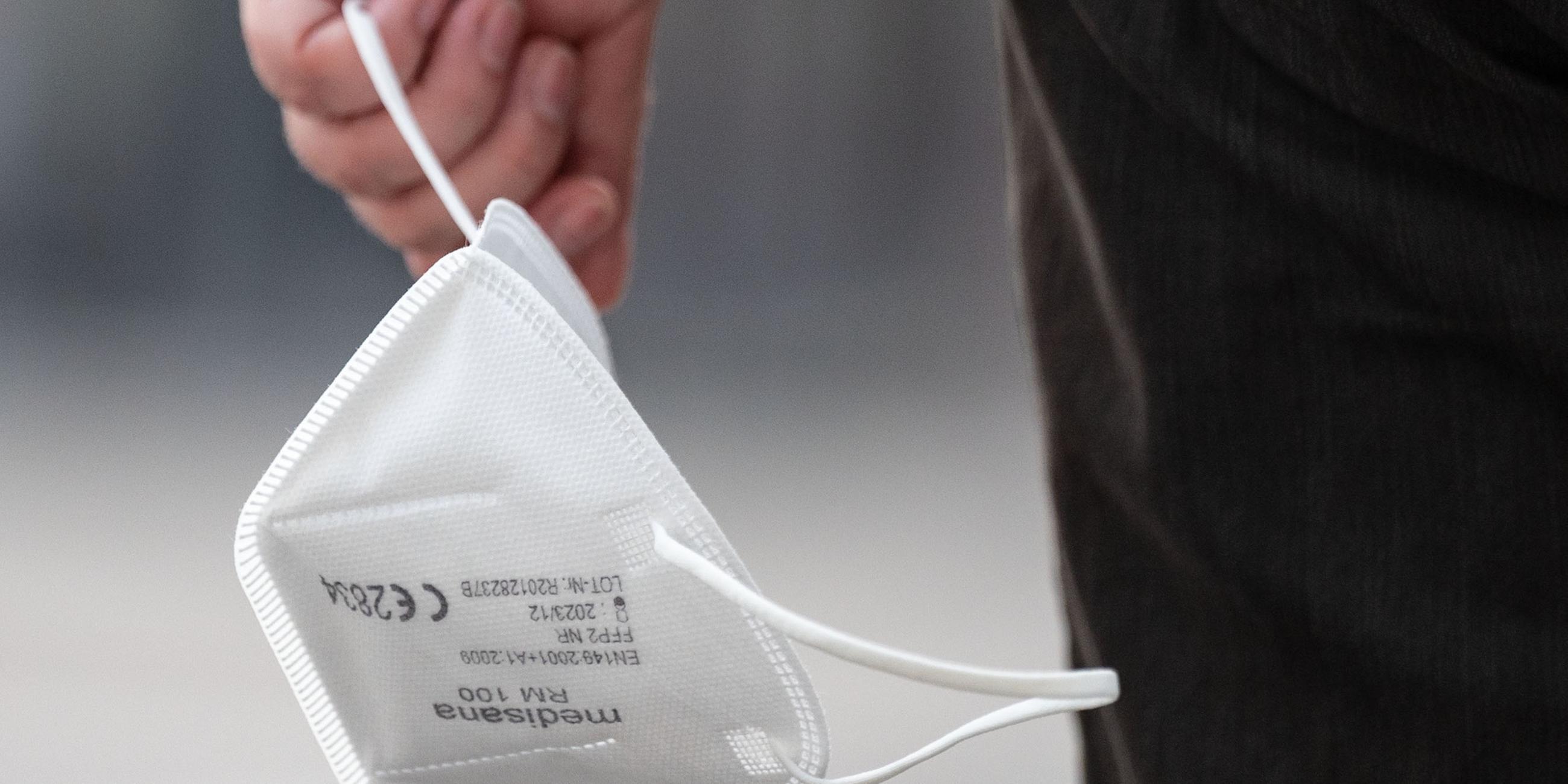 Ein Passant trägt eine FFP2-Maske in der Hand.