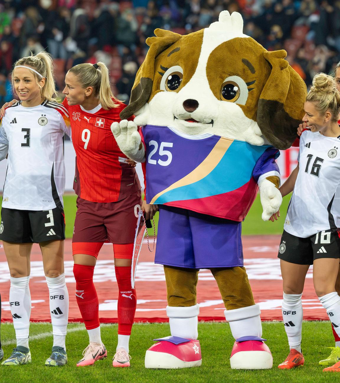Das Maskottchen Maddli mit Spielerinnen der deutschen und Schweizer Frauen-Nationalmannschaft.