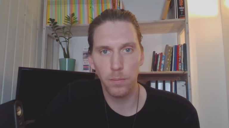 ZDF Faktenchecker Jan Schneider in einem Bürostuhl vor einem Bücherregal.