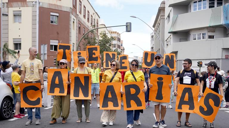 Mehrere Personen protestieren mit Plakaten während einer Demonstration gegen das Massentourismusmodell. 