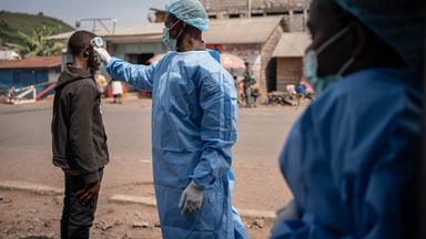 Ein Gesundheitshelfer in Schutzkittel und Maske misst in Kanyaruchinya bei Goma, Nord-Kivu, Demokratische Republik Kongo, am 27.05.2026 als Präventivmaßnahme gegen Ebola die Temperatur der Einheimischen. 