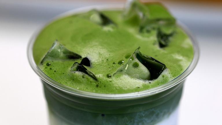 Ein Matcha-Getränk mit Milch und Eiswürfeln in einem Plastikbecher 