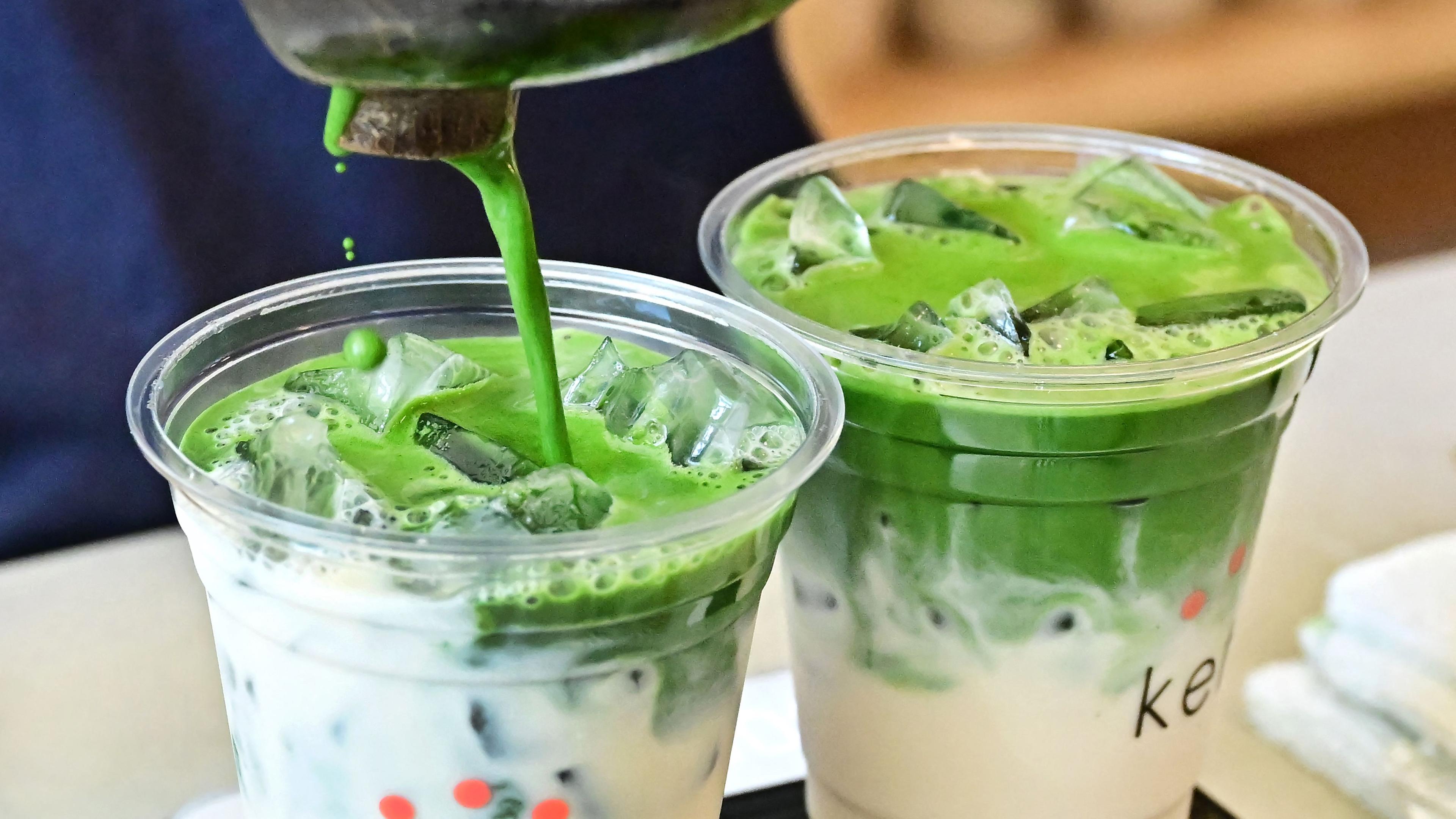 Zwei Becher Iced Matcha Latte werden zubereitet.