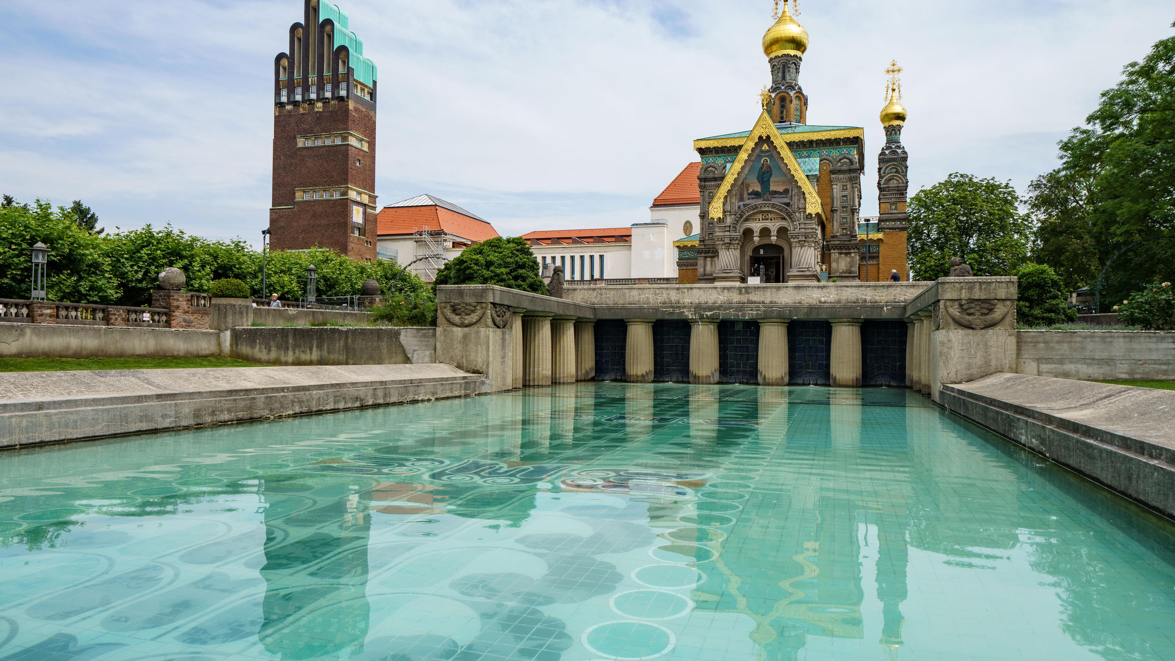 Der Hochzeitsturm, das Ausstellungsgebäude und die russische Kapelle spiegeln sich auf der Mathildenhöhe im Lilienbecken.