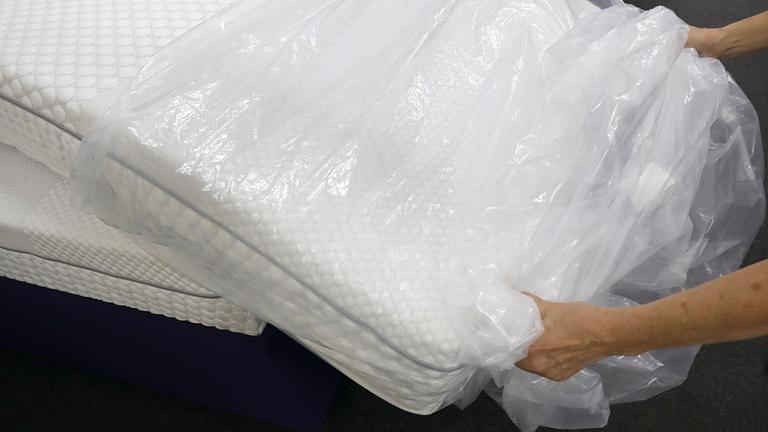 Zwei Hände greifen nach einer neuen Matratze.