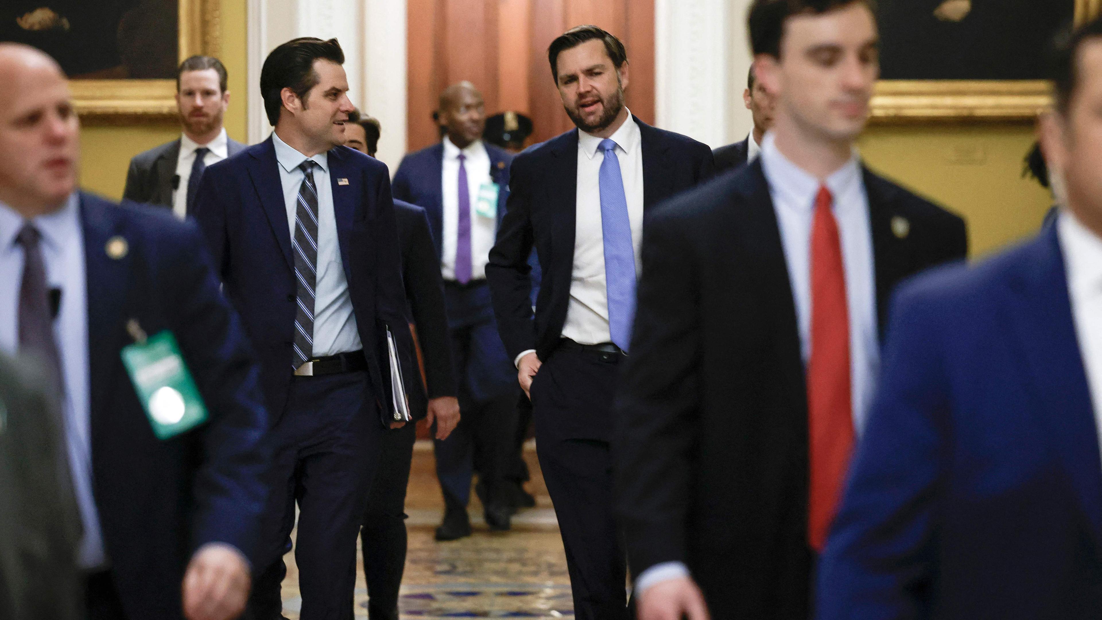 Mehrere Männer im Anzug laufen im US-Kongress auf die Kamera zu, in der Mitte sind links Matt Gaetz und rechts JD Vance zu sehen.