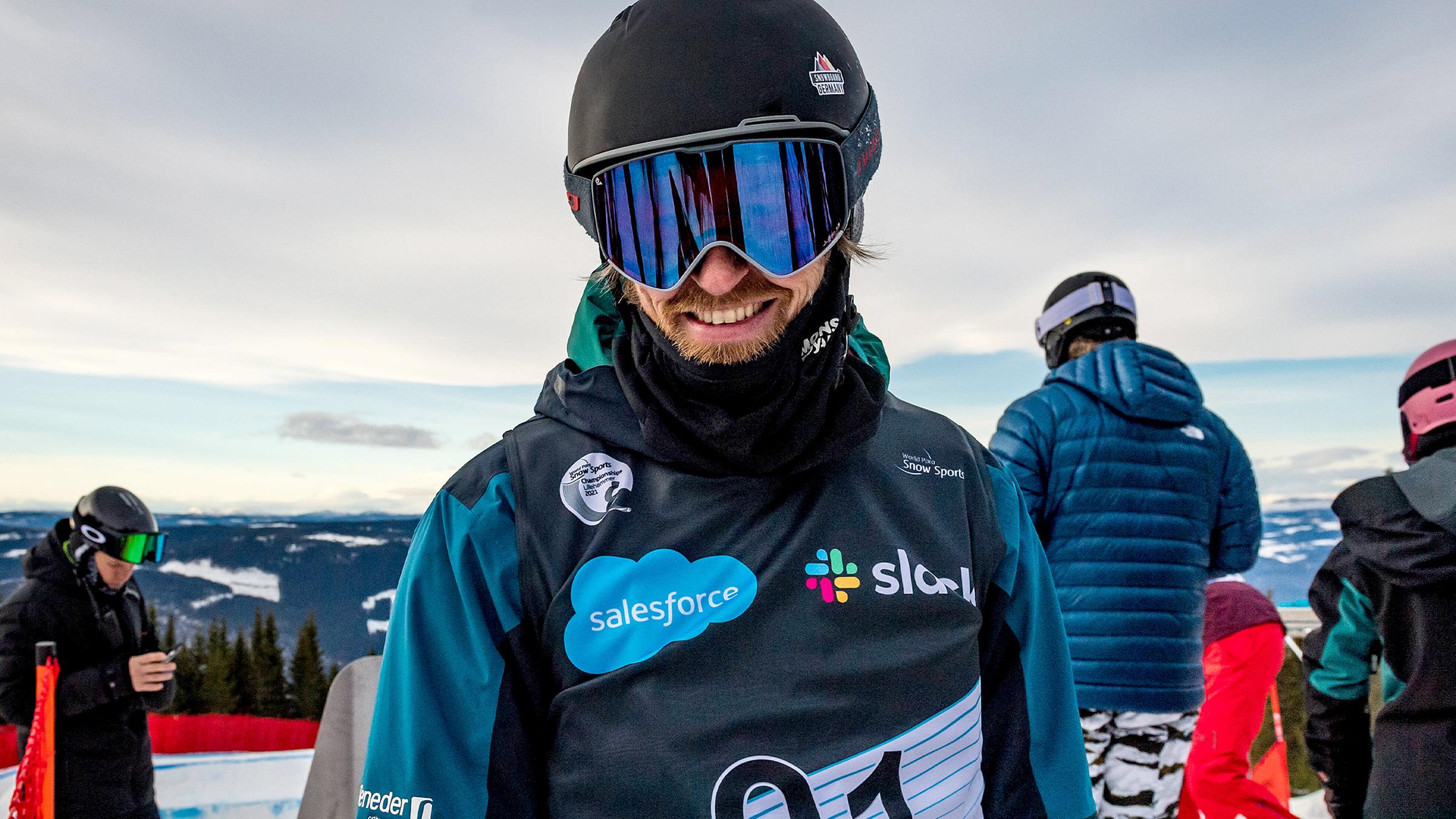 Matthias Keller trägt eine Sonnenbrille und Snowboardkleidung und lächelt in die Kamera.