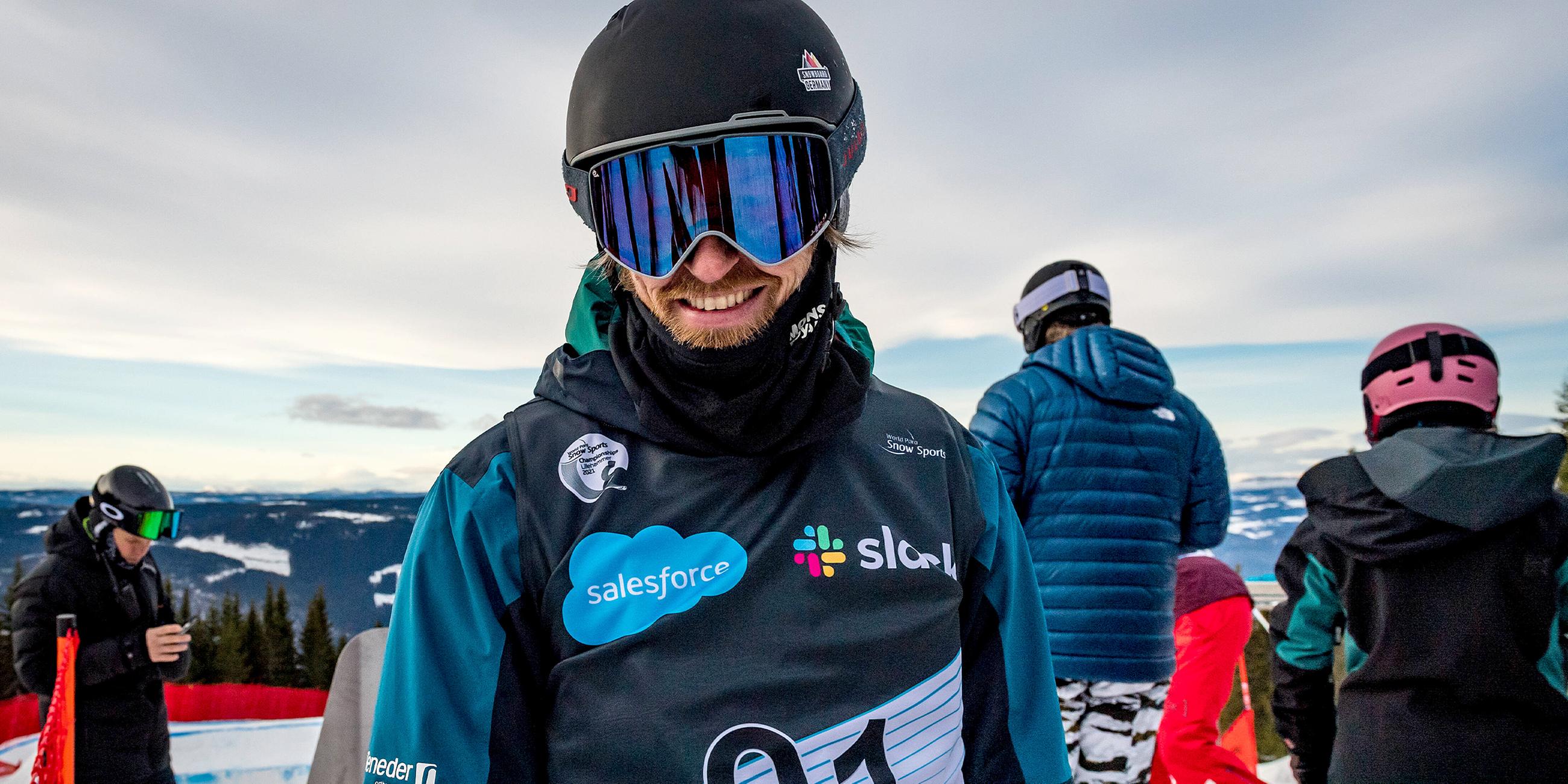 Matthias Keller trägt eine Sonnenbrille und Snowboardkleidung und lächelt in die Kamera.