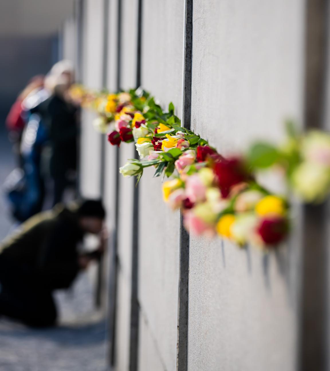 Blumen stecken nach einer zentralen Gedenkveranstaltung anlässlich von 35 Jahre friedliche Revolution und Mauerfall in der Gedenkstätte Berliner Mauer in der Hinterlandmauer.