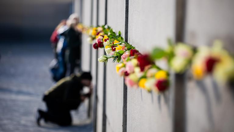 Blumen stecken nach einer zentralen Gedenkveranstaltung anlässlich von 35 Jahre friedliche Revolution und Mauerfall in der Gedenkstätte Berliner Mauer in der Hinterlandmauer.