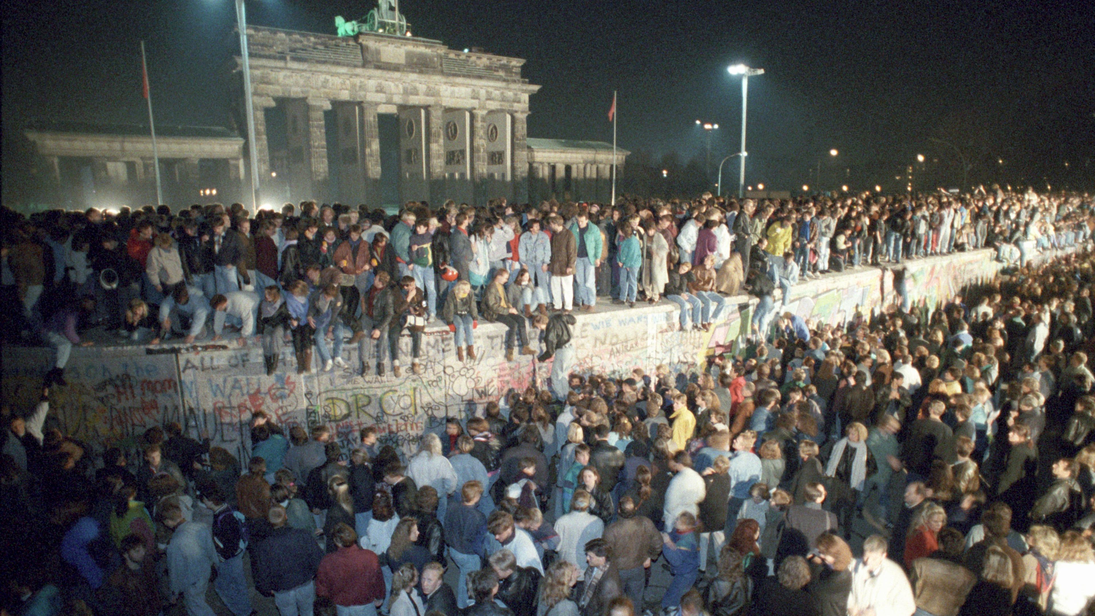 Menschen auf der Berliner Mauer vor dem Brandenburger Tor.
