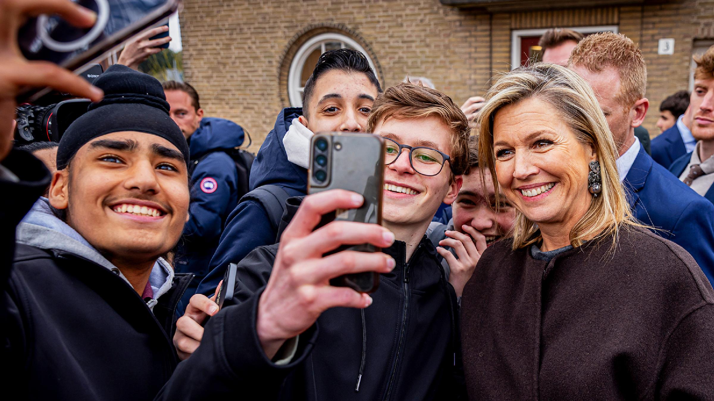 Königin Maxima der Niederlande macht Selfies mit mehreren Schülern.