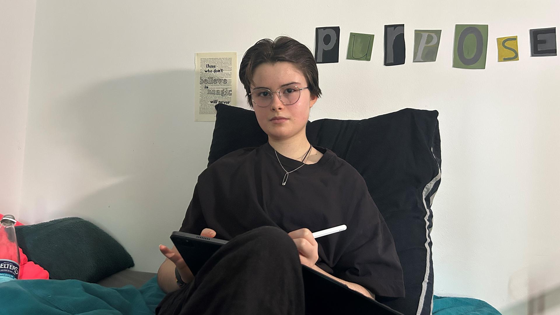Die 13-jährige Lori sitzt mit einem Tablet auf ihrem Bett. Lori hat Myalgische Enzephalomyelitis/Chronisches Fatigue Syndrom (ME/CFS).