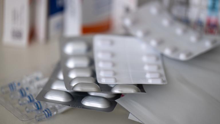 Mehrere Medikamentenblister liegen auf einem Tisch.