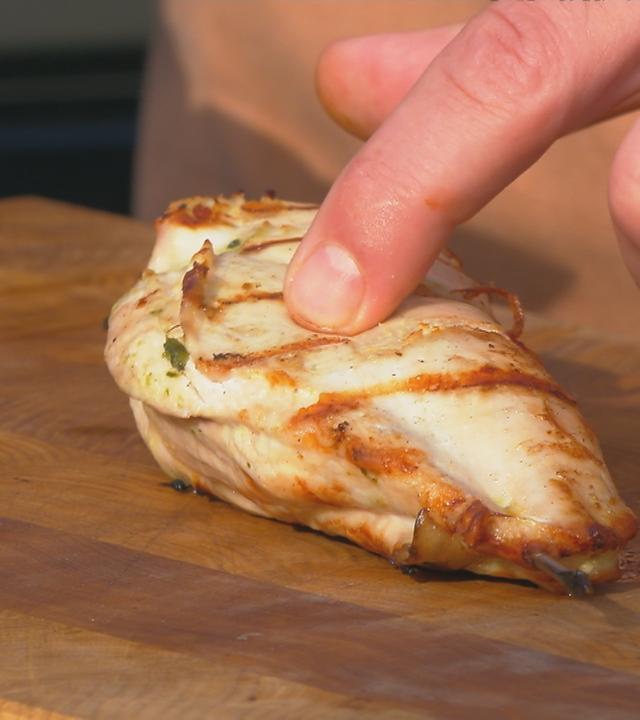Mann hat Finger auf gegrilltem Hähnchen