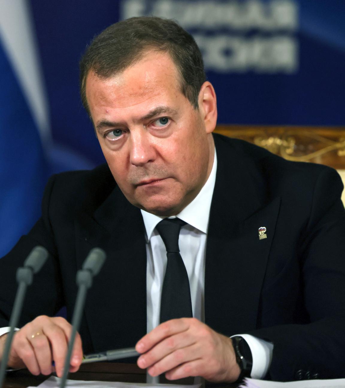 Russlands Ex-Präsident Dimitri Medwedew im Anzug vor zwei Mikrofonen.