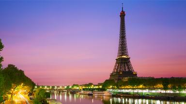 "Megacitys - Wenn es Nacht wird in Paris": Ein Fahrradfahrer fährt bei Nacht unter einer Brücke auf einem Radweg. Dahinter liegen die Lichter der Stadt Paris mit dem Eiffelturm.