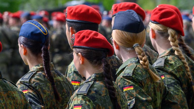Soldaten der Bundeswehr stehen in Uniform in einer Reihe und sind von hinten zu sehen.
