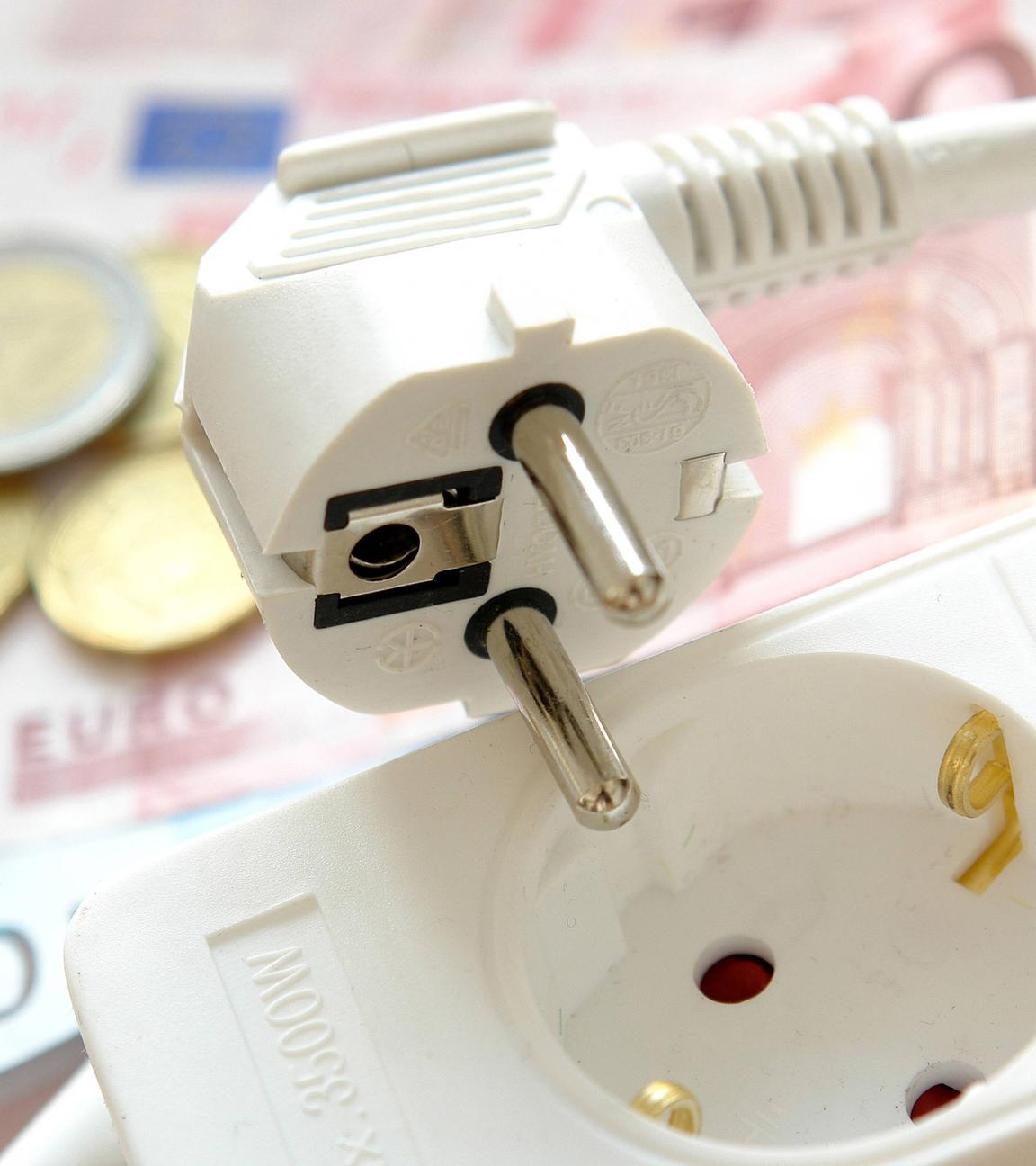 Mehrfachstecker mit Schalter, dahinter liegen Euros - als Symbolbild für Stromsparen.