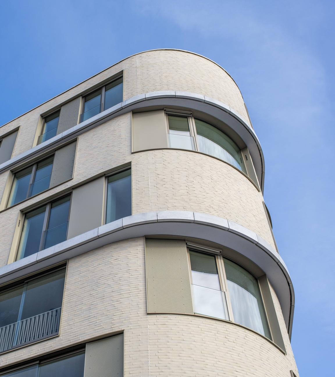 Ein modernes Mehrfamilienhaus mit großer Glasfassade und abgerundeten Ecken unter klarem blauen Himmel am 12.01.2026 in Tuttlingen.